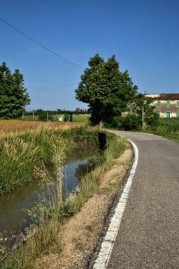 Tarlalı köy yolu ve yaz sonunda günbatımında terk edilmiş bir malikane.