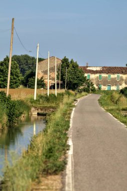 Tarlalı köy yolu ve yaz sonunda günbatımında terk edilmiş bir malikane.