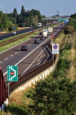 Kırsal kesimdeki İtalyan otoyolu yazın günbatımında bir köprünün üstünden görülüyor.
