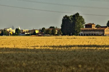 Yazın gün batımında İtalya kırsalında, taşralı bir köyde buğday tarlasında bir malikane.