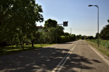 Yazın açık bir günde İtalya kırsalında boş bir yol.