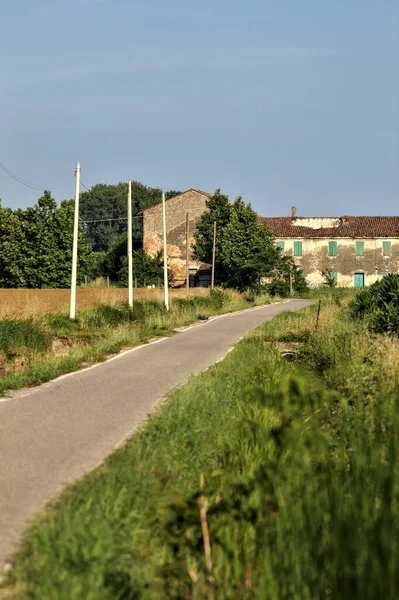 Tarlalı köy yolu ve yaz sonunda günbatımında terk edilmiş bir malikane.