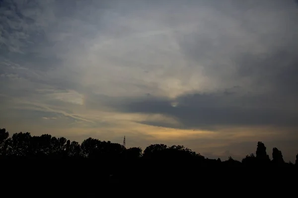 夕阳西下 天空乌云密布 树木环抱 — 图库照片