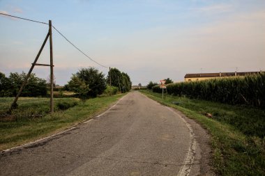 Yazın günbatımında İtalya kırsalında tarlalarla çevrili bir yol.