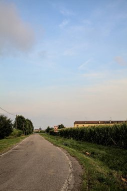 Yazın günbatımında İtalya kırsalında tarlalarla çevrili bir yol.