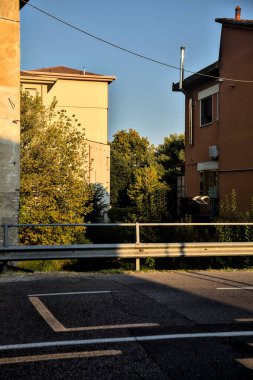 Gün batımında yerleşim alanındaki binalarla çevrili bir su deresi üzerinde yol ve köprü.