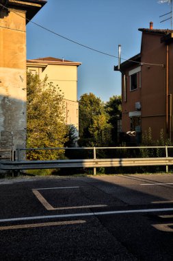 Gün batımında yerleşim alanındaki binalarla çevrili bir su deresi üzerinde yol ve köprü.