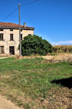 Terk edilmiş bir malikane, yazın İtalya kırsalında mısır tarlalarıyla çevrili bir ahır.
