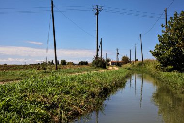 Terk edilmiş kır evi, temiz bir günde toprak bir yolun ve bir dere kenarındaki.