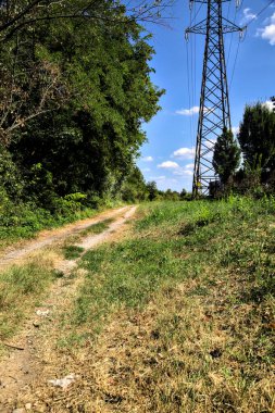 İtalya 'nın kırsal kesimlerinde elektrik direği olan bir su akıntısıyla çevrili toprak yol.