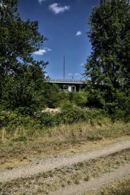 Ağaçlar ve açık gökyüzü tarafından çerçevelenmiş kırsalda küçük bir viyadük.