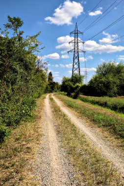 İtalya 'nın kırsal kesimlerinde elektrik direği olan bir su akıntısıyla çevrili toprak yol.