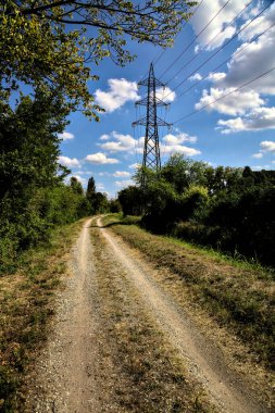 İtalya 'nın kırsal kesimlerinde elektrik direği olan bir su akıntısıyla çevrili toprak yol.