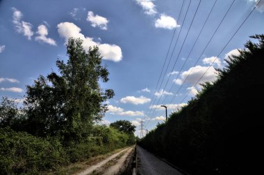 Çitin attığı gölgelerde toprak yol kırsal kesimdeki ahşap bir çitle ikiye bölünmüş.