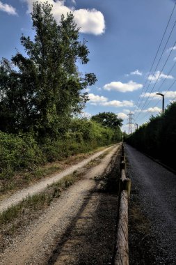 Çitin attığı gölgelerde toprak yol kırsal kesimdeki ahşap bir çitle ikiye bölünmüş.