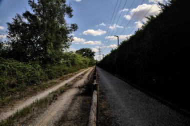Çitin attığı gölgelerde toprak yol kırsal kesimdeki ahşap bir çitle ikiye bölünmüş.
