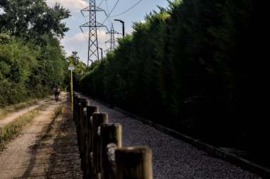 İtalyan kırsalındaki ağaçlarla çevrili pis bir patikada bisikletçi.