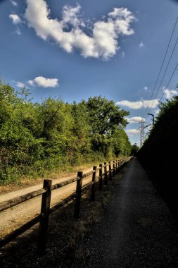 Çitin attığı gölgelerde toprak yol kırsal kesimdeki ahşap bir çitle ikiye bölünmüş.