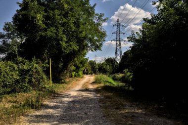 Çitin attığı gölgelerde toprak yol kırsal kesimdeki ahşap bir çitle ikiye bölünmüş.