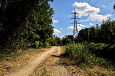 İtalya 'nın kırsal kesimlerinde elektrik direği olan bir su akıntısıyla çevrili toprak yol.