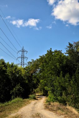 İtalya 'nın kırsal kesimlerinde elektrik direği olan bir su akıntısıyla çevrili toprak yol.