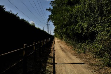 Çitin attığı gölgelerde toprak yol kırsal kesimdeki ahşap bir çitle ikiye bölünmüş.