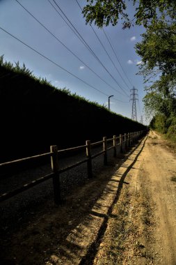 Çitin attığı gölgelerde toprak yol kırsal kesimdeki ahşap bir çitle ikiye bölünmüş.