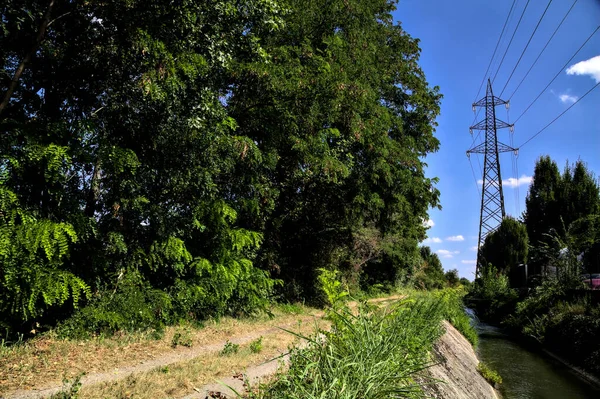 İtalya 'nın kırsal kesimlerinde elektrik direği olan bir su akıntısıyla çevrili toprak yol.