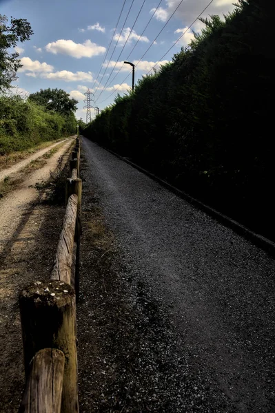 Çitin attığı gölgelerde toprak yol kırsal kesimdeki ahşap bir çitle ikiye bölünmüş.