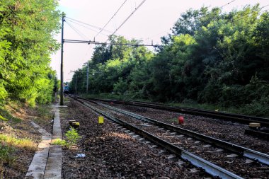 Günbatımında İtalya kırsalında bir ormanın ortasında demiryolu.