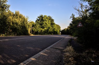 Gün batımında kırsalda ağaçlarla çevrili bir yolun kıvrımı