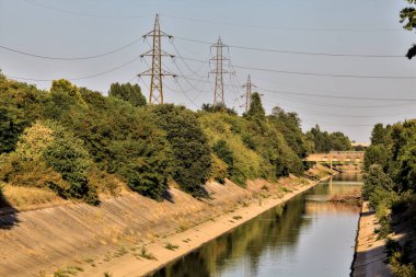 Alacakaranlıkta İtalya kırsalında elektrik direkleri olan ağaçlarla çevrili saptırma kanalı