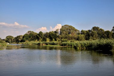 Gün batımında suya yansıyan bir ormanla çevrili bir nehirdeki kanal.