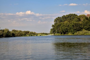 Gün batımında suya yansıyan bir ormanla çevrili bir nehirdeki kanal.