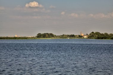 Alacakaranlıkta İtalya kırsalındaki bir nehirden görülebilen, açıkça görülebilen bir kilisesi olan antik bir köyün silueti.