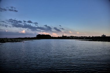 Alacakaranlıkta İtalya kırsalındaki bir nehirden görülebilen, açıkça görülebilen bir kilisesi olan antik bir köyün silueti.