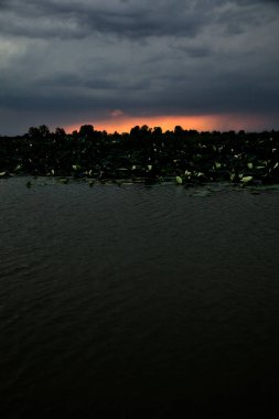 Yağmur yağmadan önce İtalya kırsalında bir nehrin üzerinde gün batımı