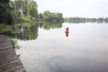 Floating buoy casted in the water on a cloudy day next to the lakeshore