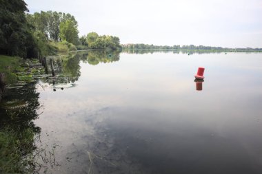 Floating buoy casted in the water on a cloudy day next to the lakeshore