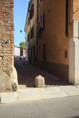 Narrow cobbled alley in the shade seen from the edge of a street in the sunlight