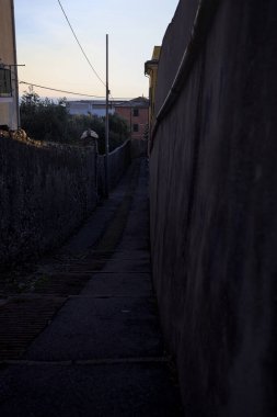 Passageway between concrete walls climbing on a cliff next to buildings at sunset