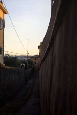 Passageway between concrete walls climbing on a cliff next to buildings at sunset