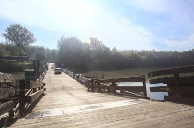 Marcaria, İtalya - 6 Ekim 2025 - Güneşli bir günde üzerinden geçen arabalarla Oglio nehri üzerindeki Pontoon köprüsü