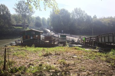 Marcaria, İtalya - 6 Ekim 2025 - Güneşli bir günde üzerinden geçen arabalarla Oglio nehri üzerindeki Pontoon köprüsü