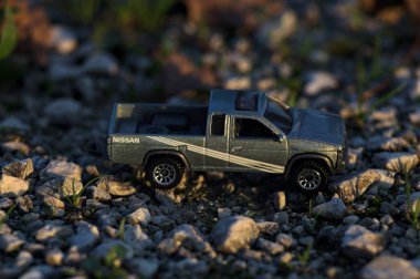 Stradella, İtalya - 10 Ekim 2025 - 2017 Nissan Hardbody 'in çakıl taşı ve çimenlerin gün batımında kibrit kutusu kopyası