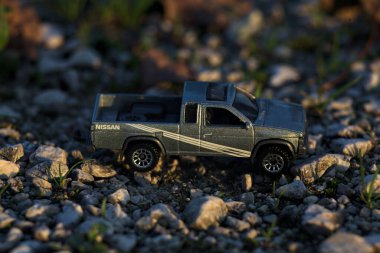 Stradella, İtalya - 10 Ekim 2025 - 2017 Nissan Hardbody 'in çakıl taşı ve çimenlerin gün batımında kibrit kutusu kopyası