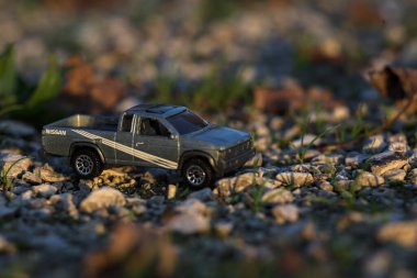 Stradella, İtalya - 10 Ekim 2025 - 2017 Nissan Hardbody 'in çakıl taşı ve çimenlerin gün batımında kibrit kutusu kopyası