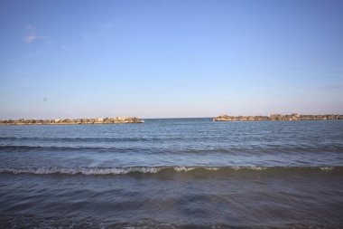 Gün batımında deniz kenarında dalgalar ufukta.