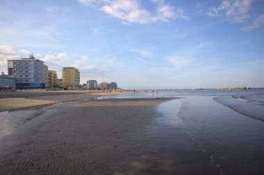 Gün batımında alçak gelgit sırasında kumsalın yanındaki binalar