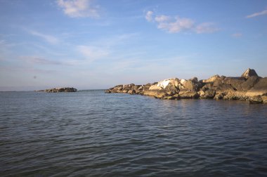 Gün batımında açık ve güneşli bir günde sahil kenarında dalgalı su.